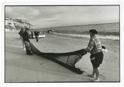 Pescadores a desenrolar rede na praia